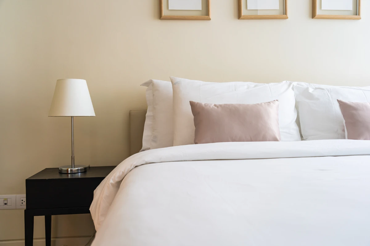 Freshly made hotel-style bed with white linens and soft pillows